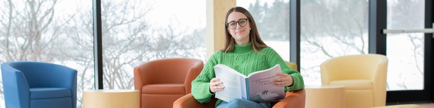 ͯŮ climate change student Zoe Furlotte reading a textbook with bright windows in the background